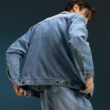 Παρουσιάζει την εφαρμογή και το στυλ ενός τζιν μπουφάν και τζιν παντελονιού από πίσω, αναδεικνύοντας πώς κάθεται το μπουφάν όταν φοριέται.