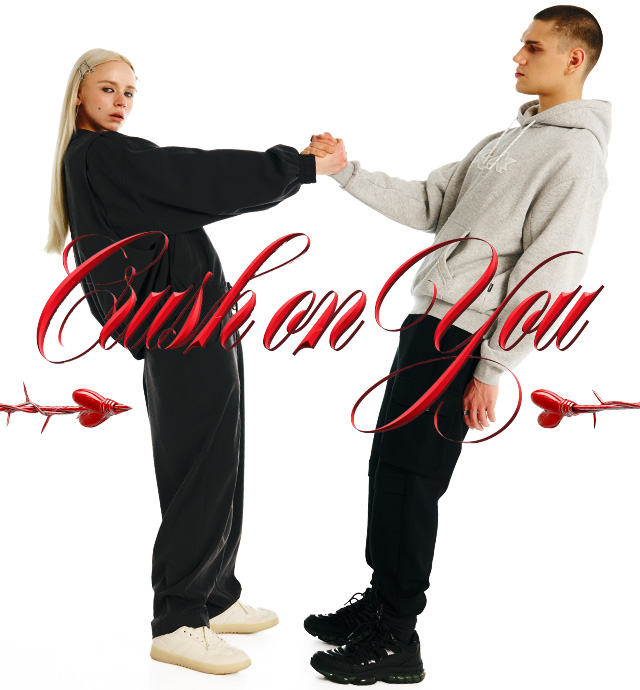 Two people stand facing each other, holding hands while leaning back slightly. The phrase "Crush on You" appears in bold cursive letters, decorated with heart-shaped arrows. The scene conveys a playful and romantic vibe.